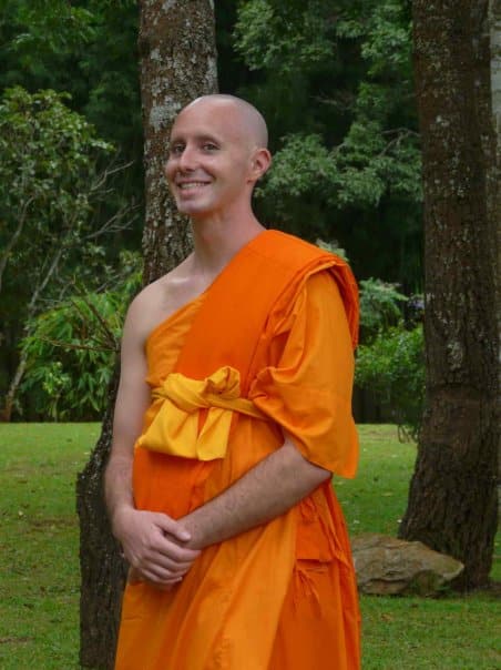 Sean Fargo as a Buddhist monk in the Thai Theravada tradition, smiling in monastery forest